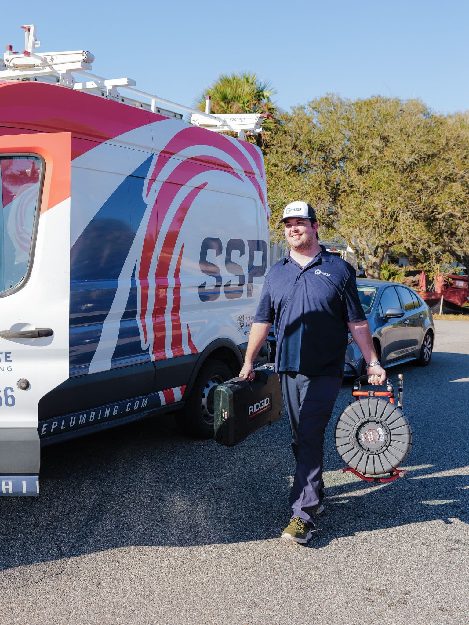 Sunshine State Plumbing technician walking from a wrapped company van with tools