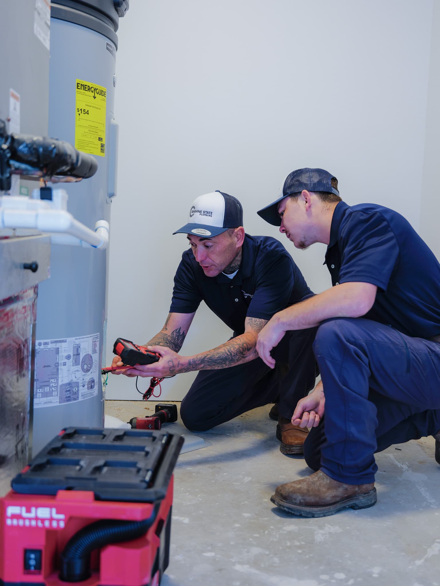 Two Sunshine State Plumbing technicians servicing a water heater