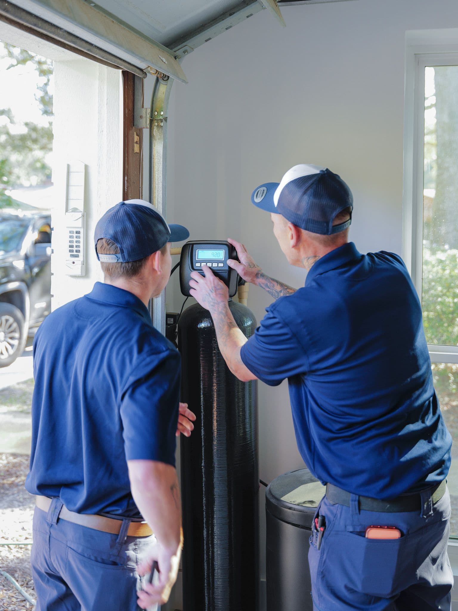 Two Sunshine State Plumbing technicians installing a water softener