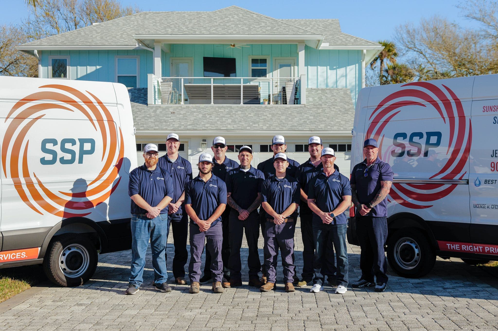 The Sunshine State Plumbing service team standing between two wrapped company vans