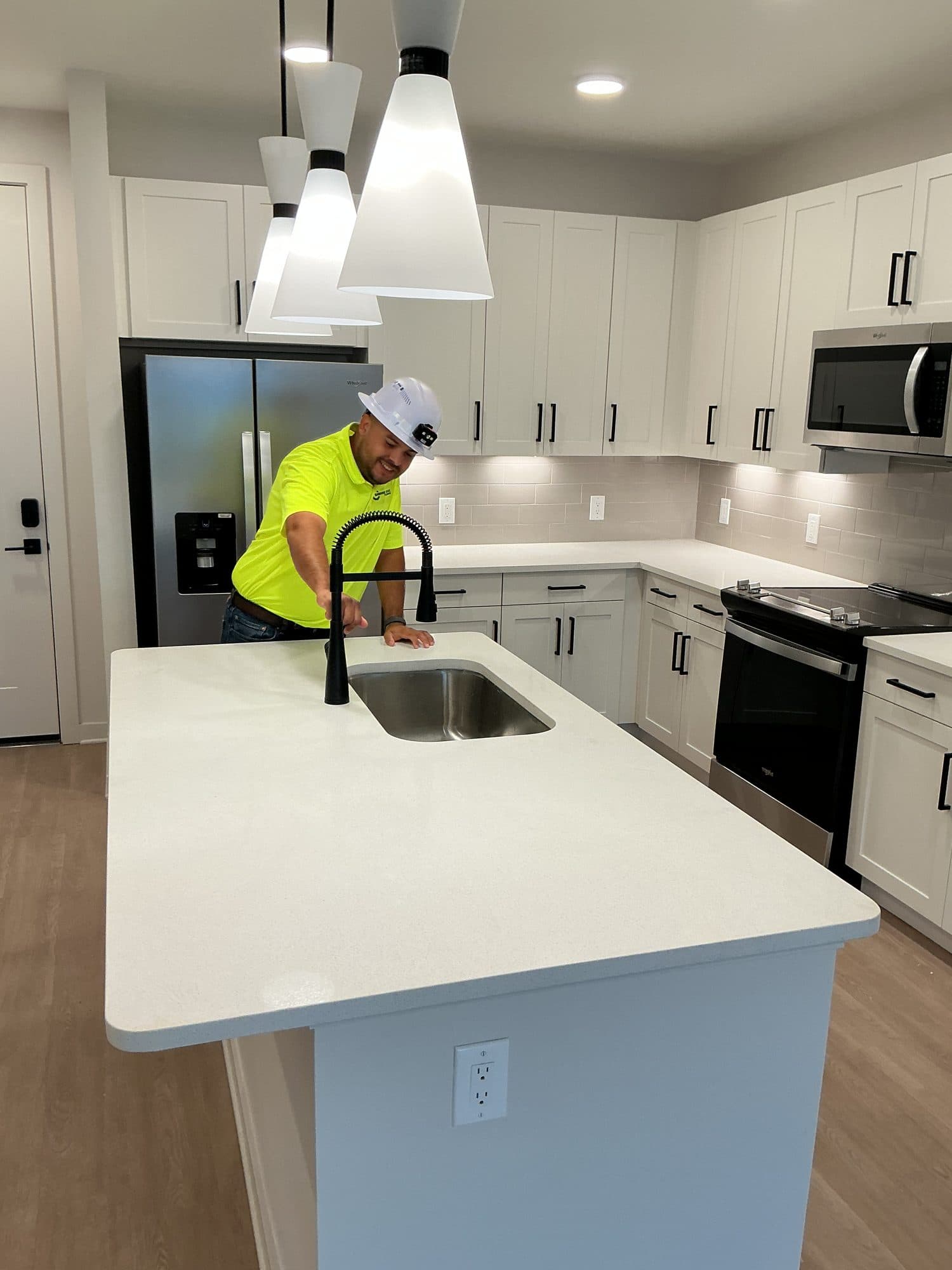Sunshine State Plumbing technician setting a kitchen island faucet during unit trim-out
