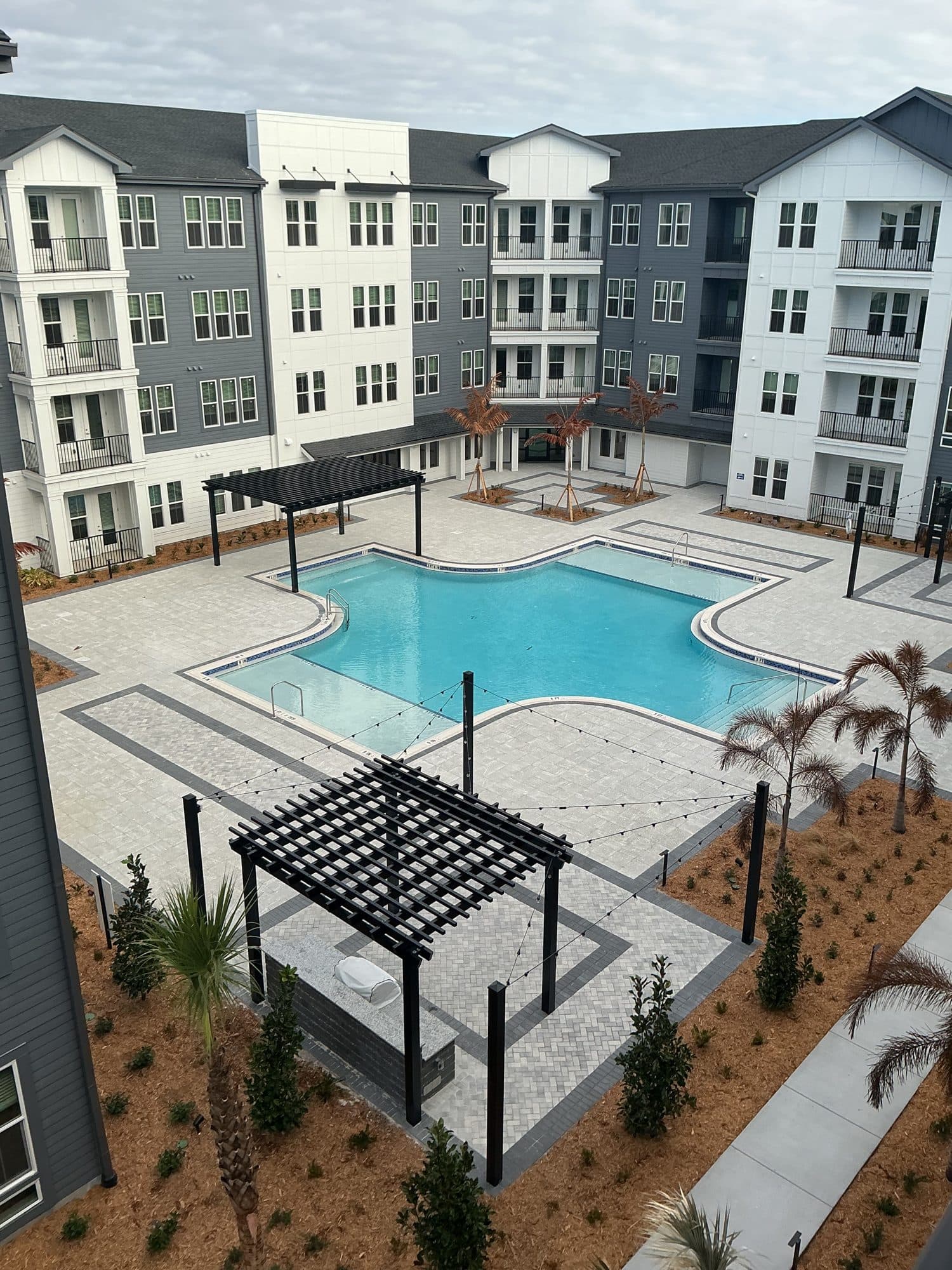 Completed apartment courtyard with resort-style pool and pergolas