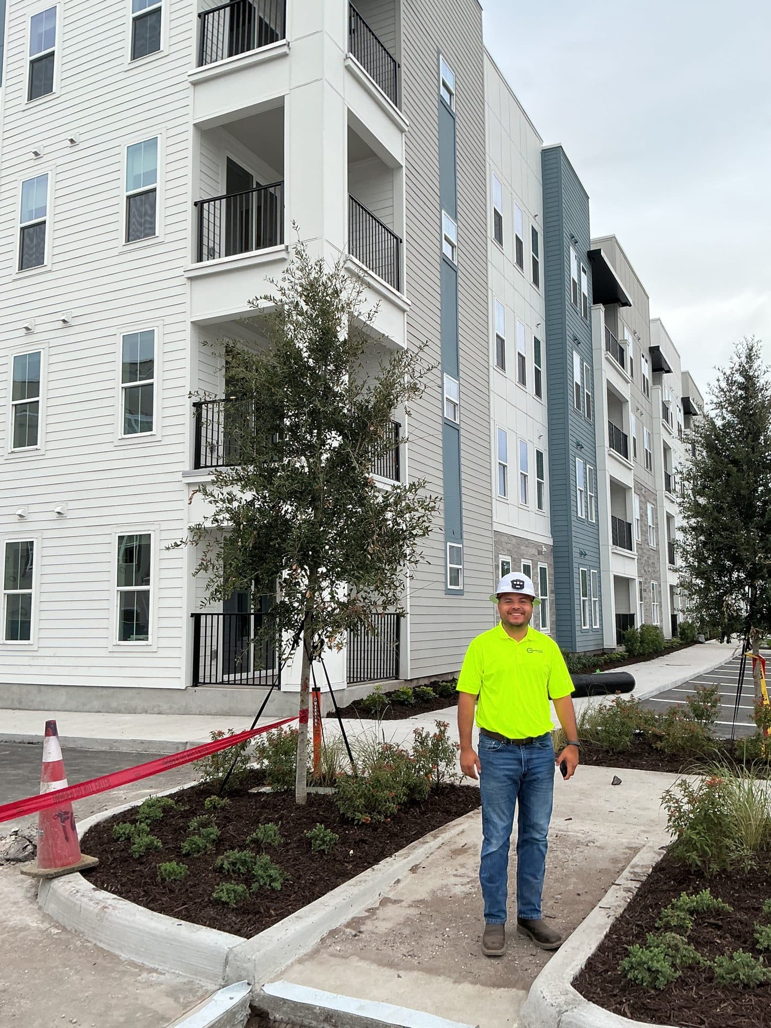 Sunshine State Plumbing technician outside a completed multifamily apartment building